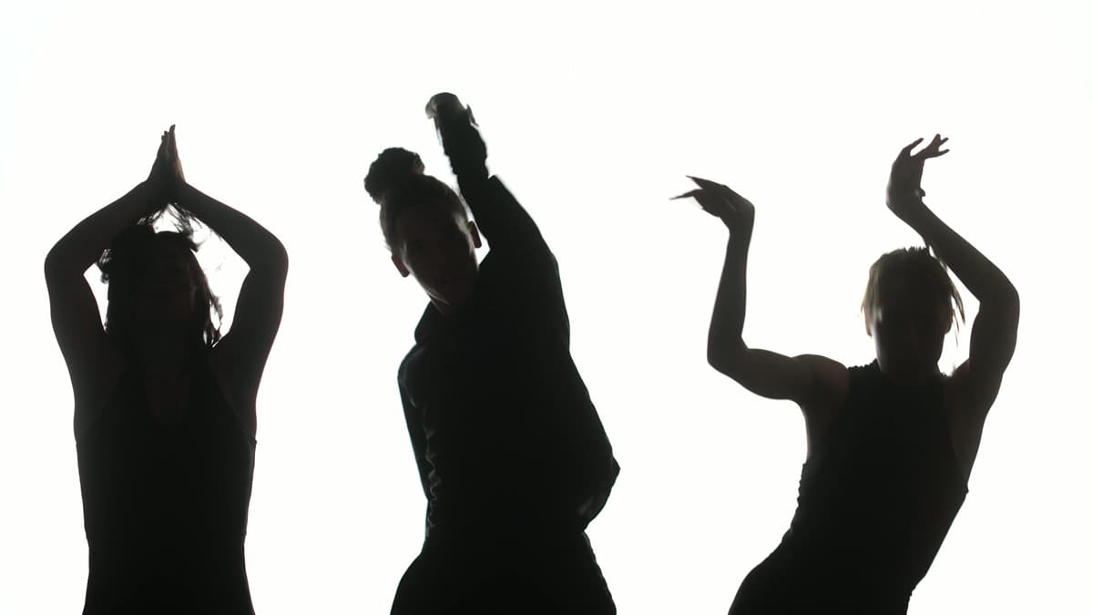 Three silhouettes of dancers in front of a white background.